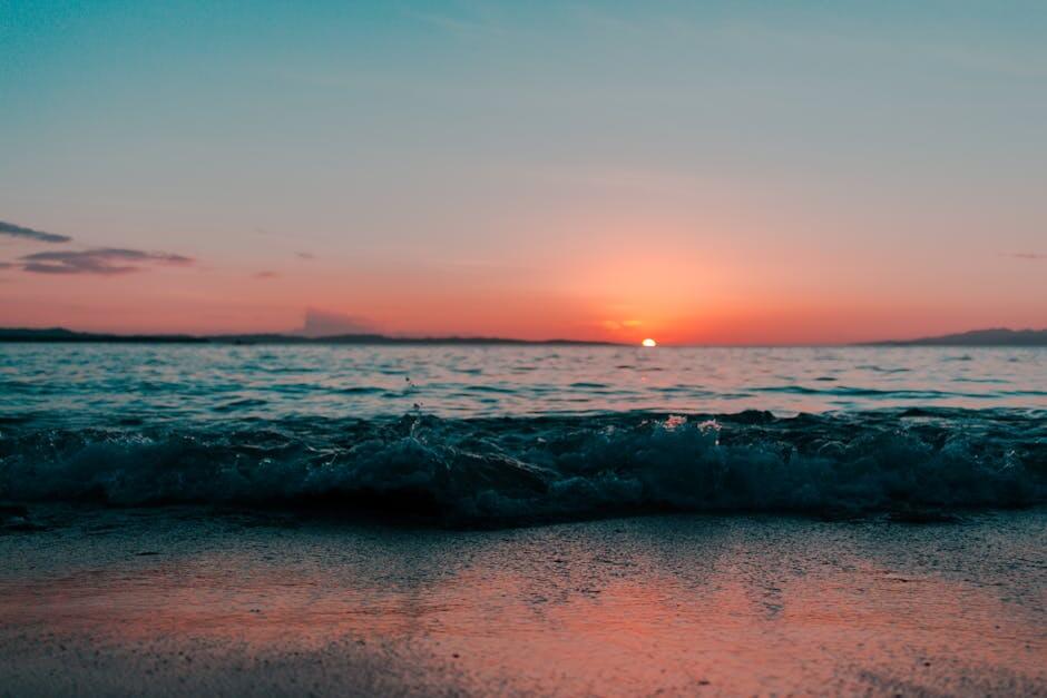 Captivating sunset over gentle ocean waves and sandy beach, creating a serene seascape perfect for relaxation and reflection.