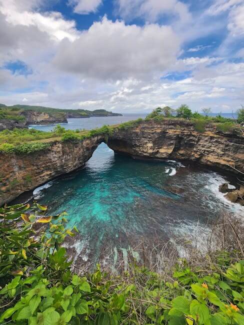 pexels-photo-14516182-14516182 Breathtaking view of a natural rock arch over turquoise waters with lush greenery.
