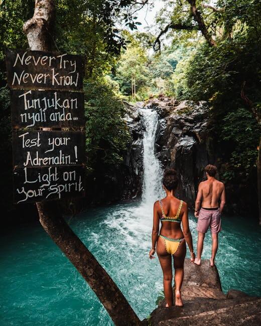 A couple stands before a stunning waterfall in Bali, embracing adventure and nature.
