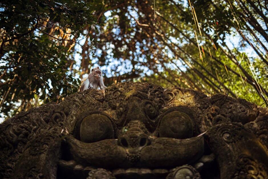 A monkey sitting on an ornate sculpture in Ubud's lush monkey forest.