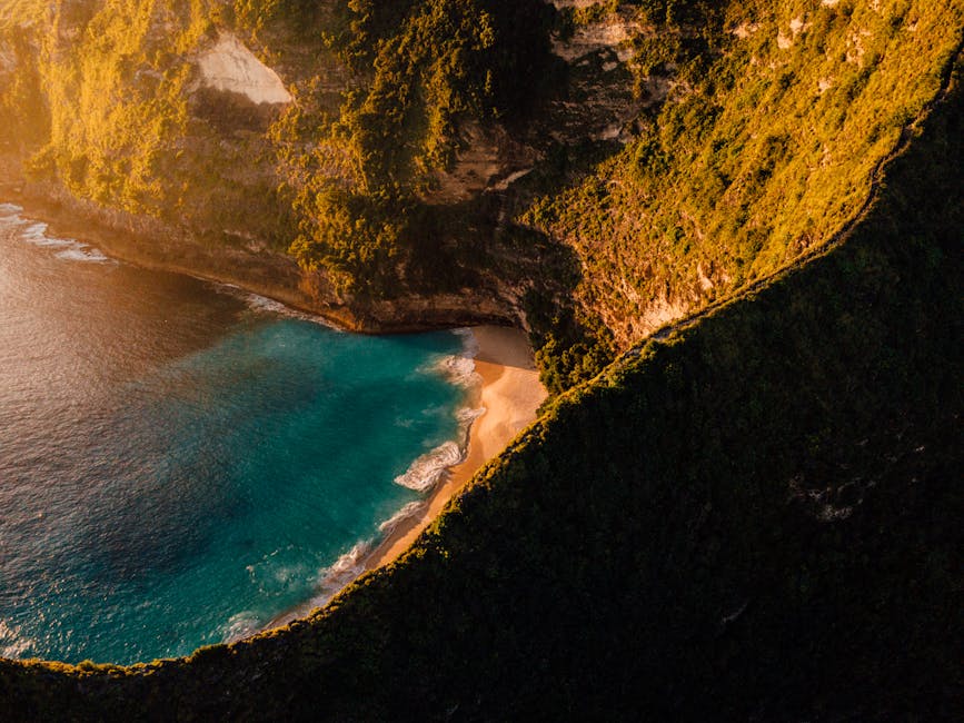 A breathtaking aerial view of Bali's cliffs and turquoise beach at sunset, highlighting nature's beauty.