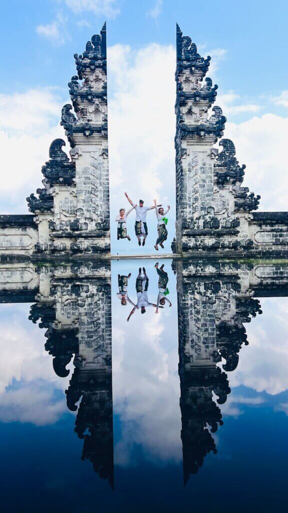 Tourists enjoy the iconic Gates of Heaven in Bali, reflected in serene water.