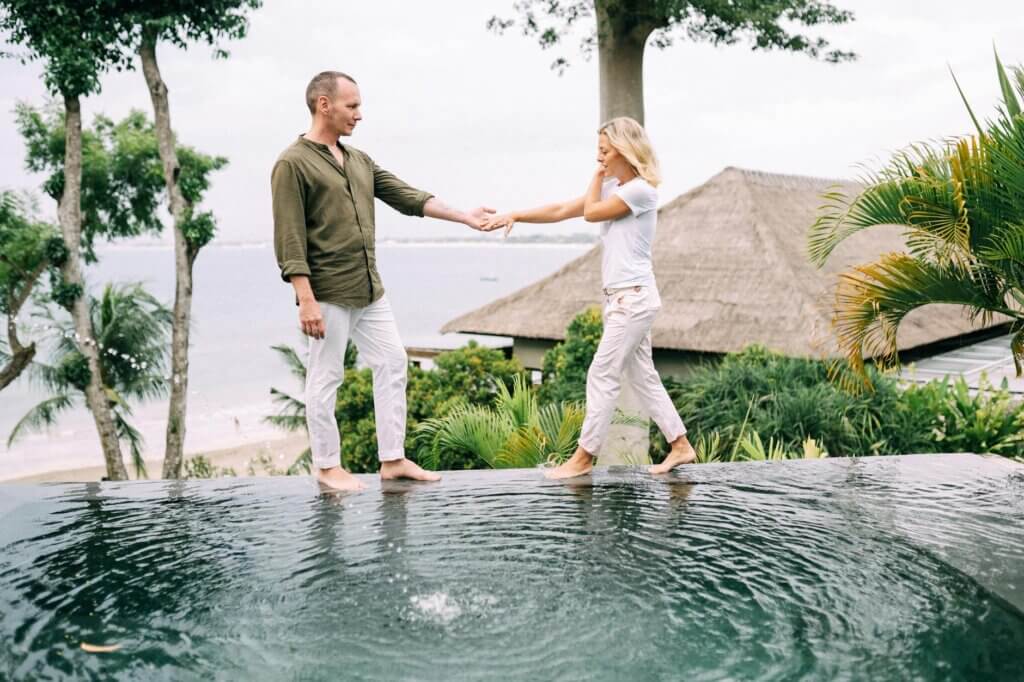 Couple holding hands and enjoying a tropical vacation by the poolside.