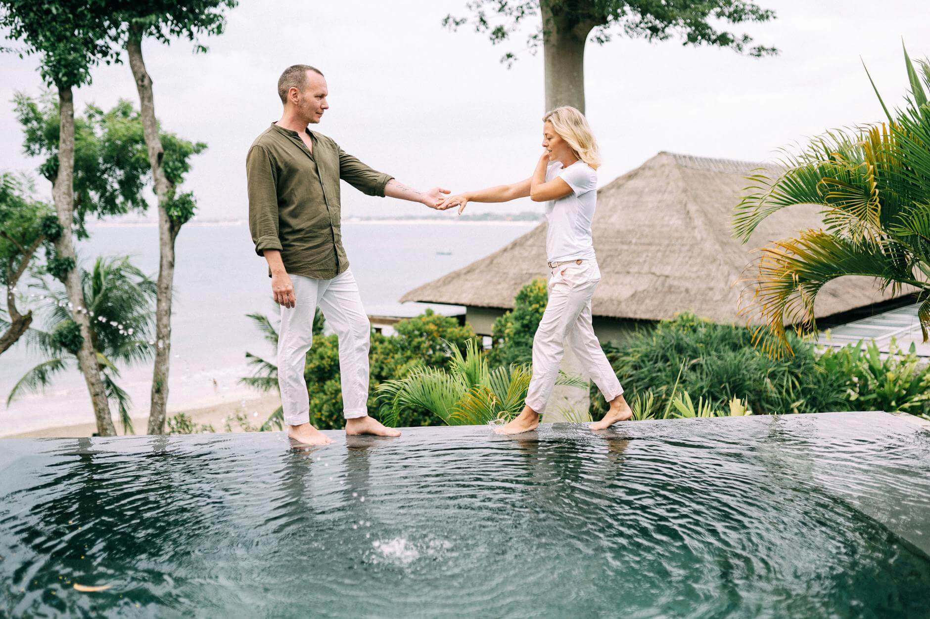 Couple holding hands and enjoying a tropical vacation by the poolside.
