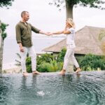 Couple holding hands and enjoying a tropical vacation by the poolside.