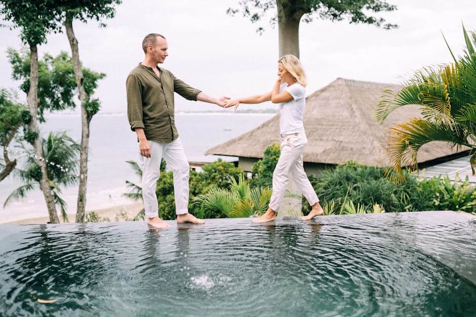 Couple holding hands and enjoying a tropical vacation by the poolside.
