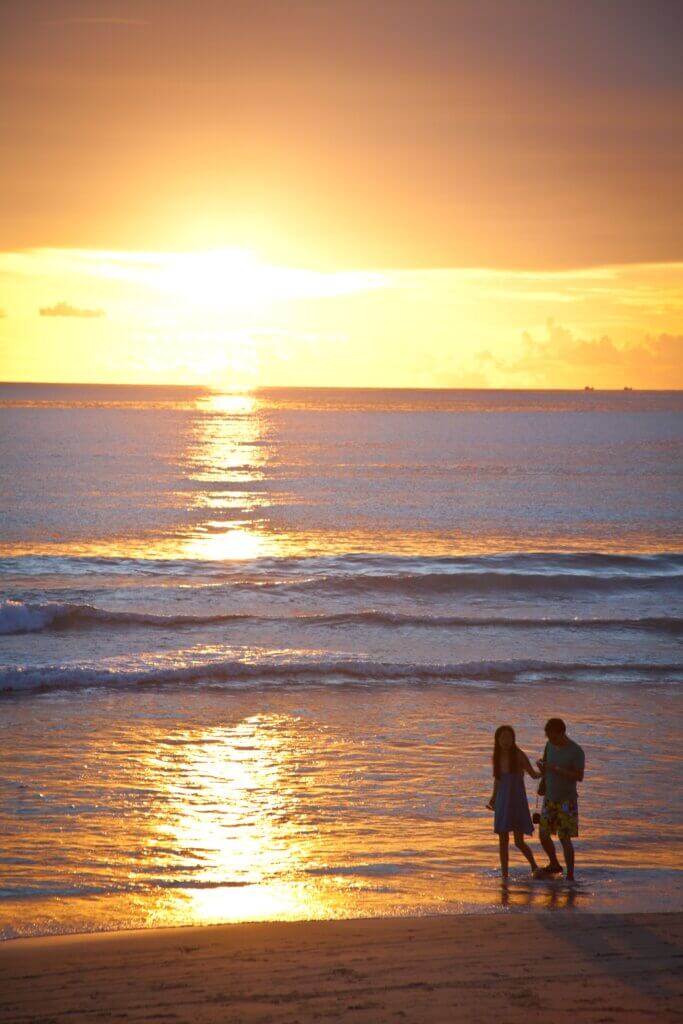 Couple enjoying a serene walk along the beach during a stunning sunset.