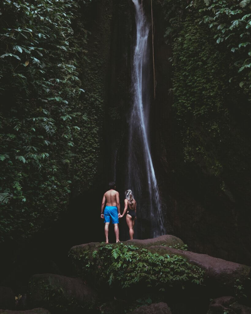 Couple standing in front of a lush waterfall in Bali, symbolizing connection and tranquility.